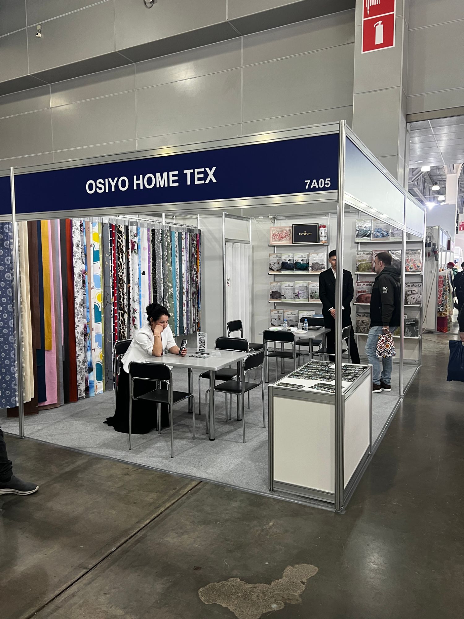 A home textiles stand at Interfabric Moscow showing rolls of printed fabric.